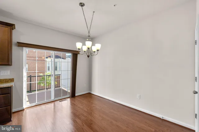 a view of a livingroom with a chandelier wooden floor and windows