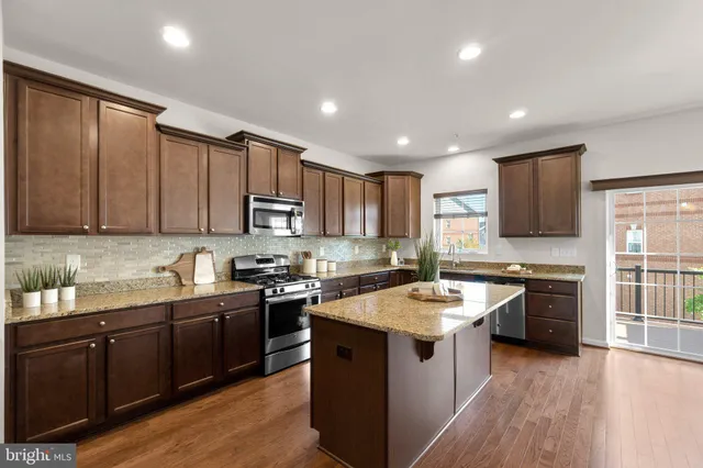a kitchen with granite countertop stainless steel appliances sink stove microwave and cabinets