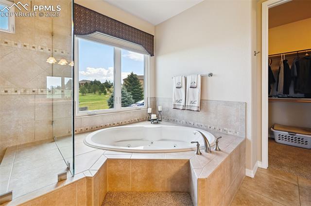1918 Bashley Road Monument, CO 80132 - Photo 25 of 48 Full bathroom featuring a tub with jets, tile patterned flooring, a spacious closet, and tiled shower