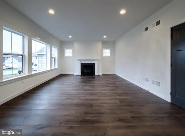 an empty room with wooden floor fireplace and windows
