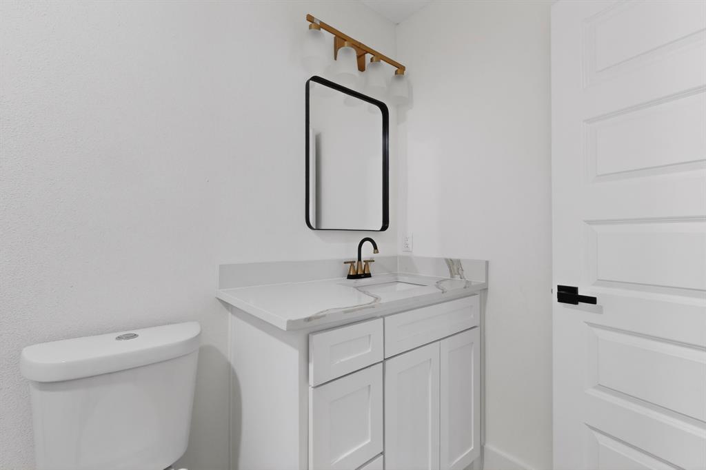 2219 Wilbur Street Dallas, TX 75224 - Photo 16 of 37 a bathroom with a toilet sink vanity and mirror