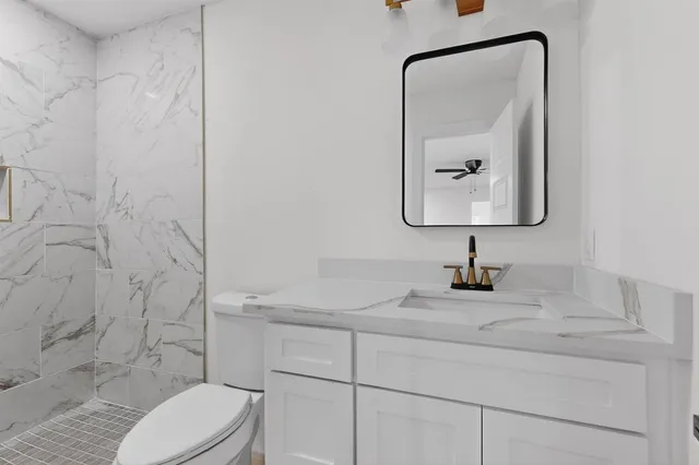 a bathroom with a toilet sink vanity and mirror