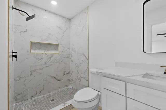 a bathroom with a toilet sink vanity and mirror