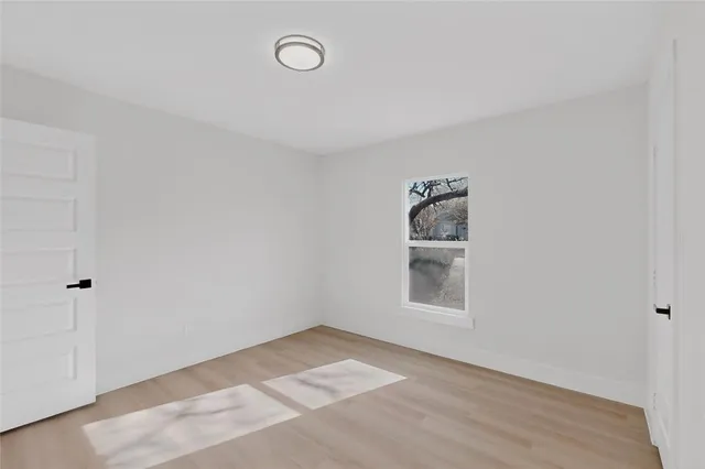 a view of an empty room with a window and wooden floor