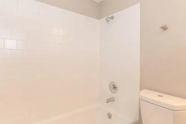 a bathroom with a granite countertop sink a toilet and shower