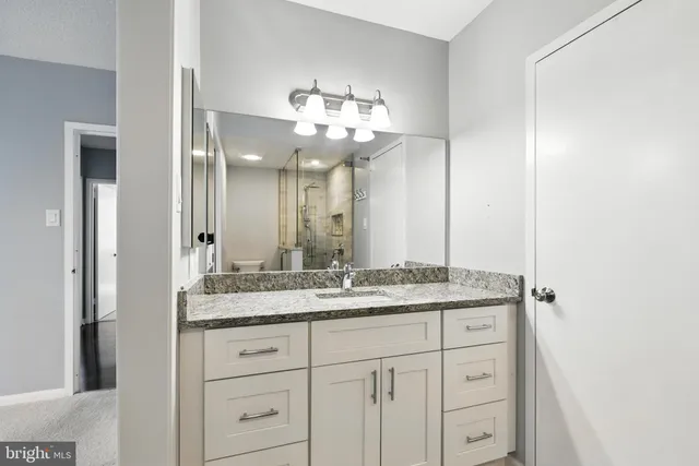a bathroom with a granite countertop double vanity sink and mirror