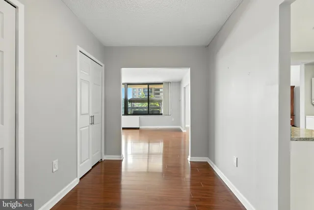 a view of an empty room with wooden floor and a window