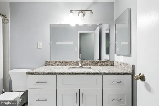 a bathroom with a granite countertop sink vanity and mirror