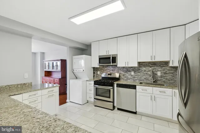 a kitchen with stainless steel appliances granite countertop a refrigerator sink stove microwave and cabinets