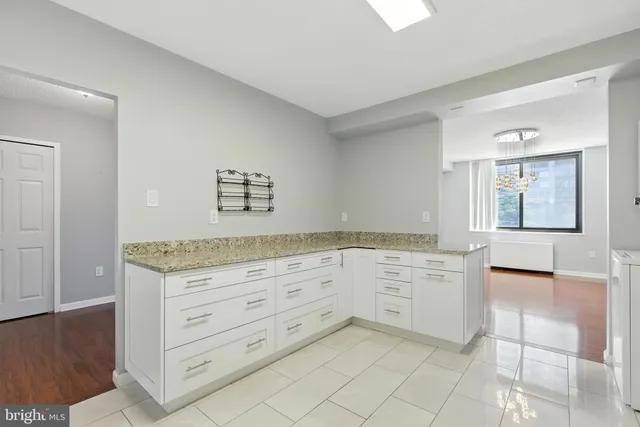 a kitchen with granite countertop white cabinets and window