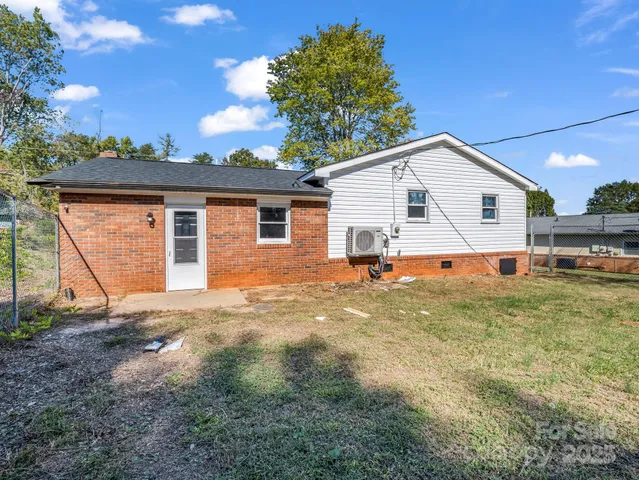 a view of a white house next to a yard with big trees