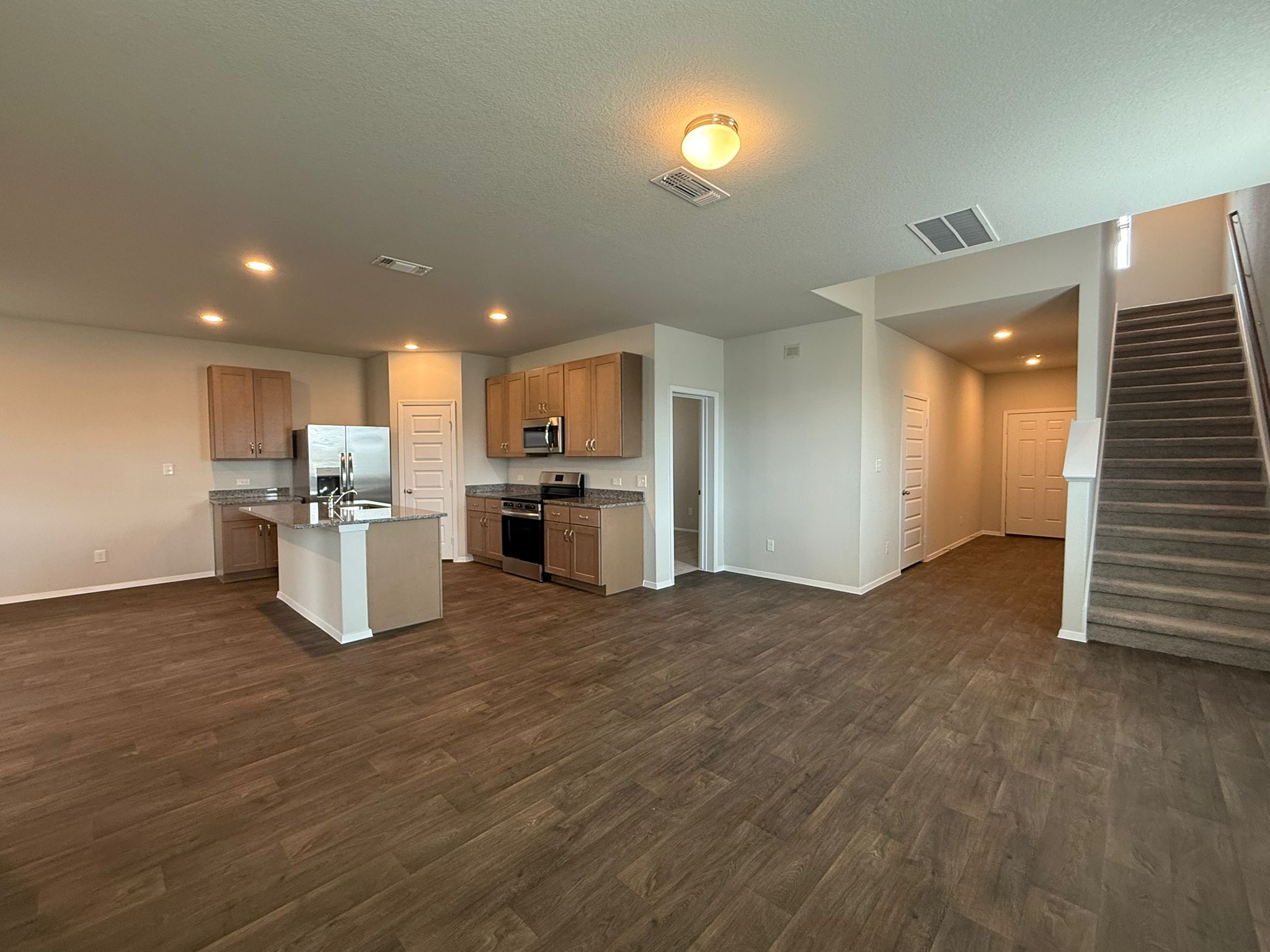 2603 Totley Road Manor, TX 78653 - Photo 7 of 37 Kitchen with stainless steel appliances, dark wood-type flooring, a kitchen island with sink, recessed lighting, and a textured ceiling
