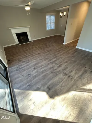an empty room with wooden floor and chandelier
