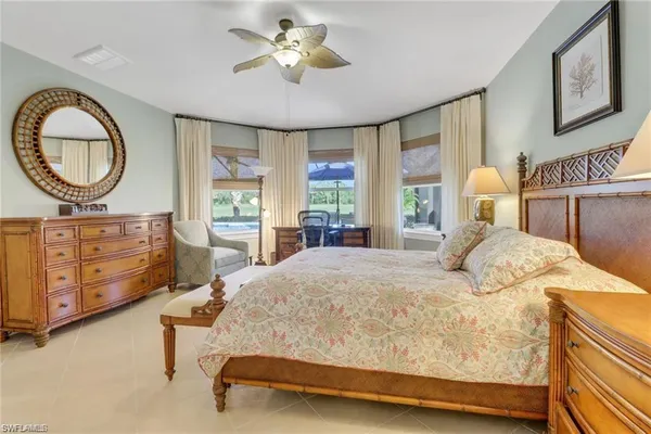 a bedroom with a bed a mirror on dresser and a chandelier