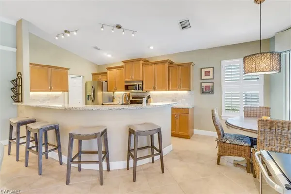 a kitchen with kitchen island a dining table chairs cabinets and a sink