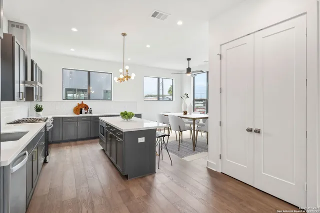 a kitchen that has a lot of white cabinets and stainless steel appliances