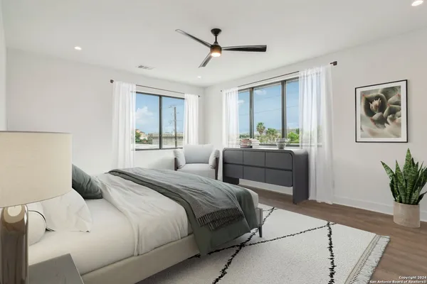 an empty room with wooden floor fan and windows