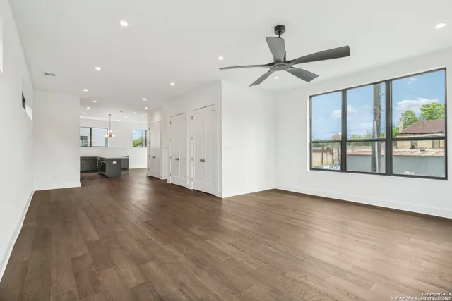 a view of an empty room with wooden floor and a ceiling fan