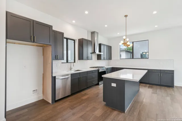 a kitchen with stainless steel appliances granite countertop wooden floors and sink
