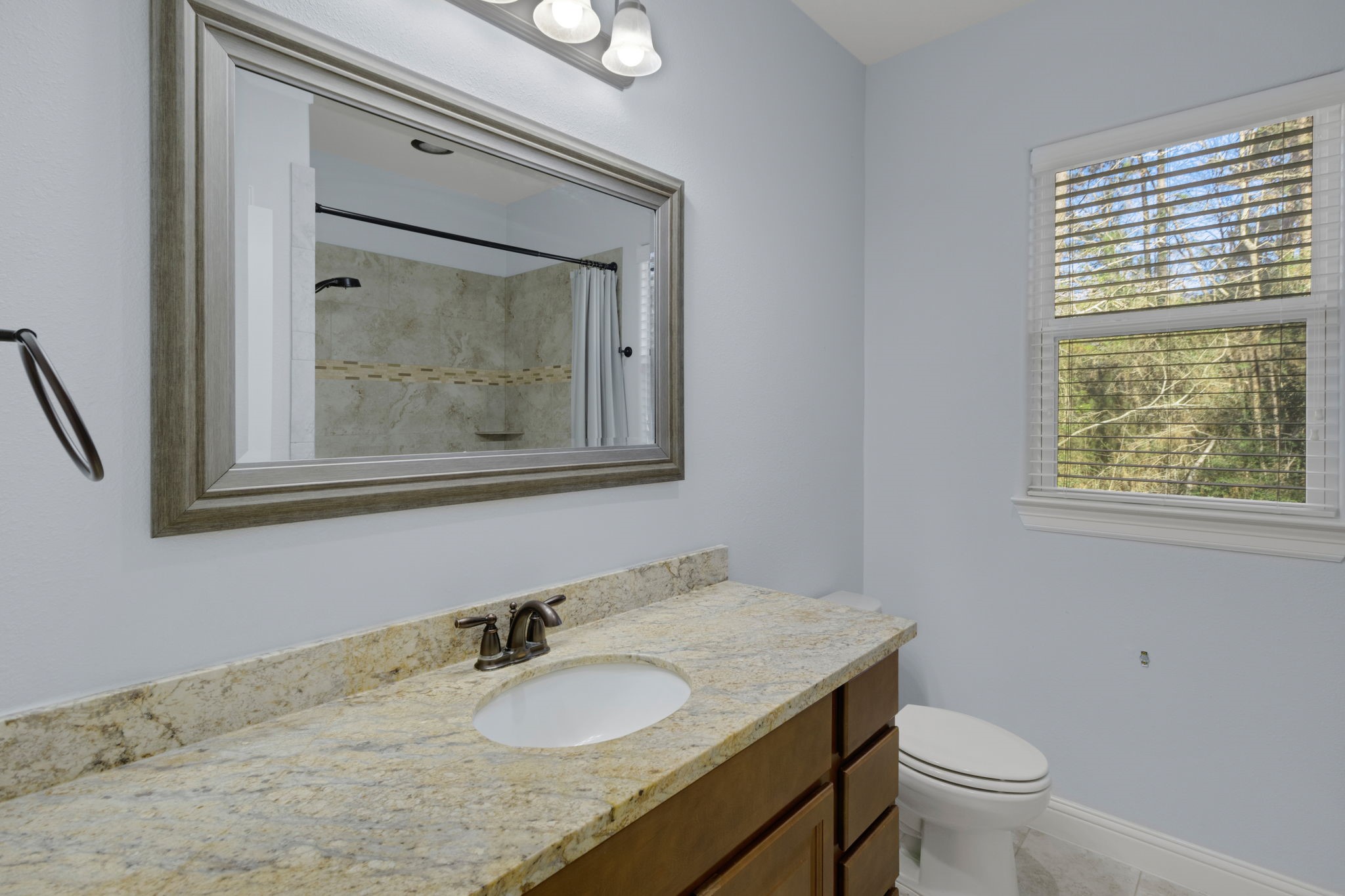 30 Beachwood Way Coldspring, TX 77331 - Photo 25 of 47 a bathroom with a granite countertop toilet a sink and a mirror