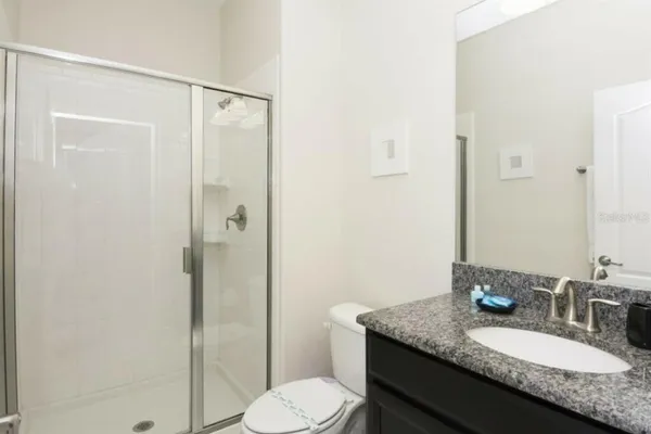 a bathroom with a granite countertop sink toilet and shower