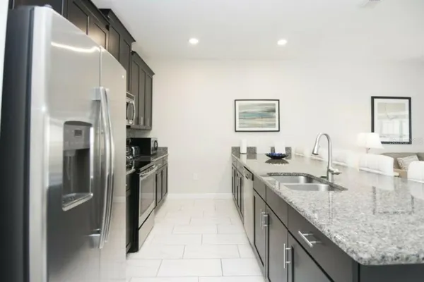 a large kitchen with granite countertop a sink and refrigerator