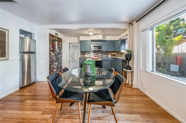 a kitchen with stainless steel appliances granite countertop a stove a refrigerator a sink dishwasher and a dining table with wooden floor