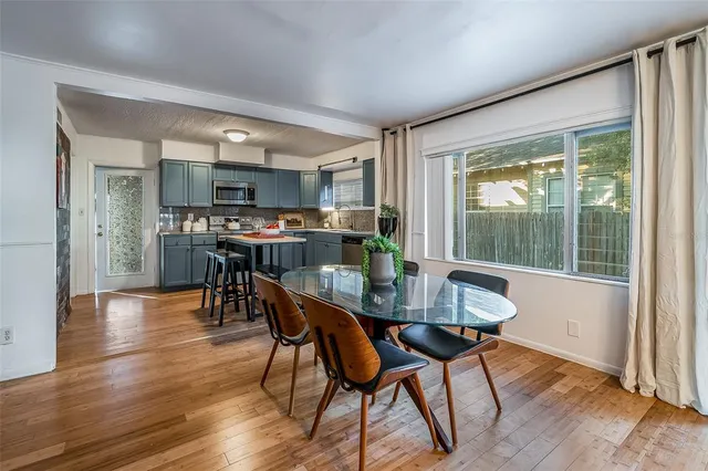 a kitchen with stainless steel appliances a table chairs a refrigerator a stove a sink and a dining table with wooden floor