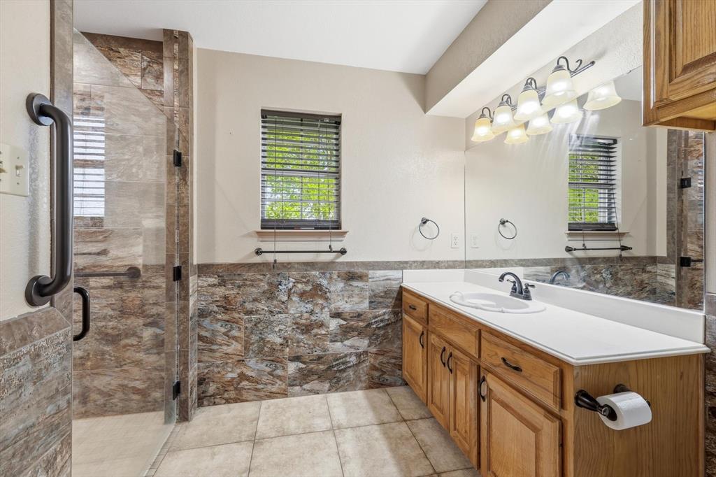 135 Private Road 2202 Decatur, TX 76234 - Photo 21 of 40 Bathroom featuring vanity, a shower stall, a wainscoted wall, light tile patterned floors, and tile walls