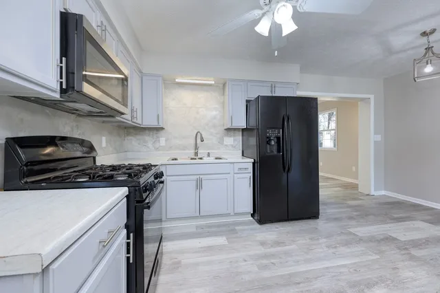 wooden floor in an empty room with a chandelier fan