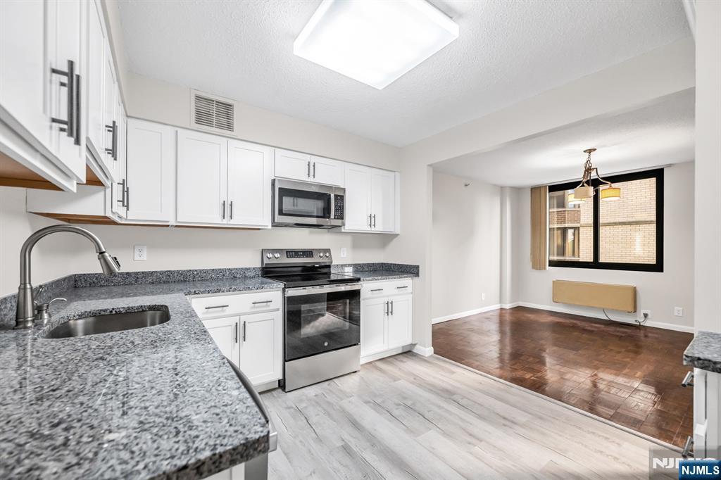 a kitchen with stainless steel appliances granite countertop a sink stove microwave and refrigerator