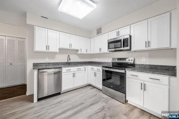 a kitchen with granite countertop white cabinets and stainless steel appliances