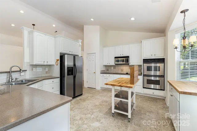 a kitchen with stainless steel appliances granite countertop a refrigerator and a stove top oven