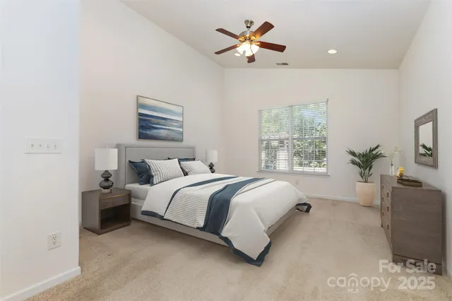 a spacious bedroom with a bed a window and potted plant on a dresser