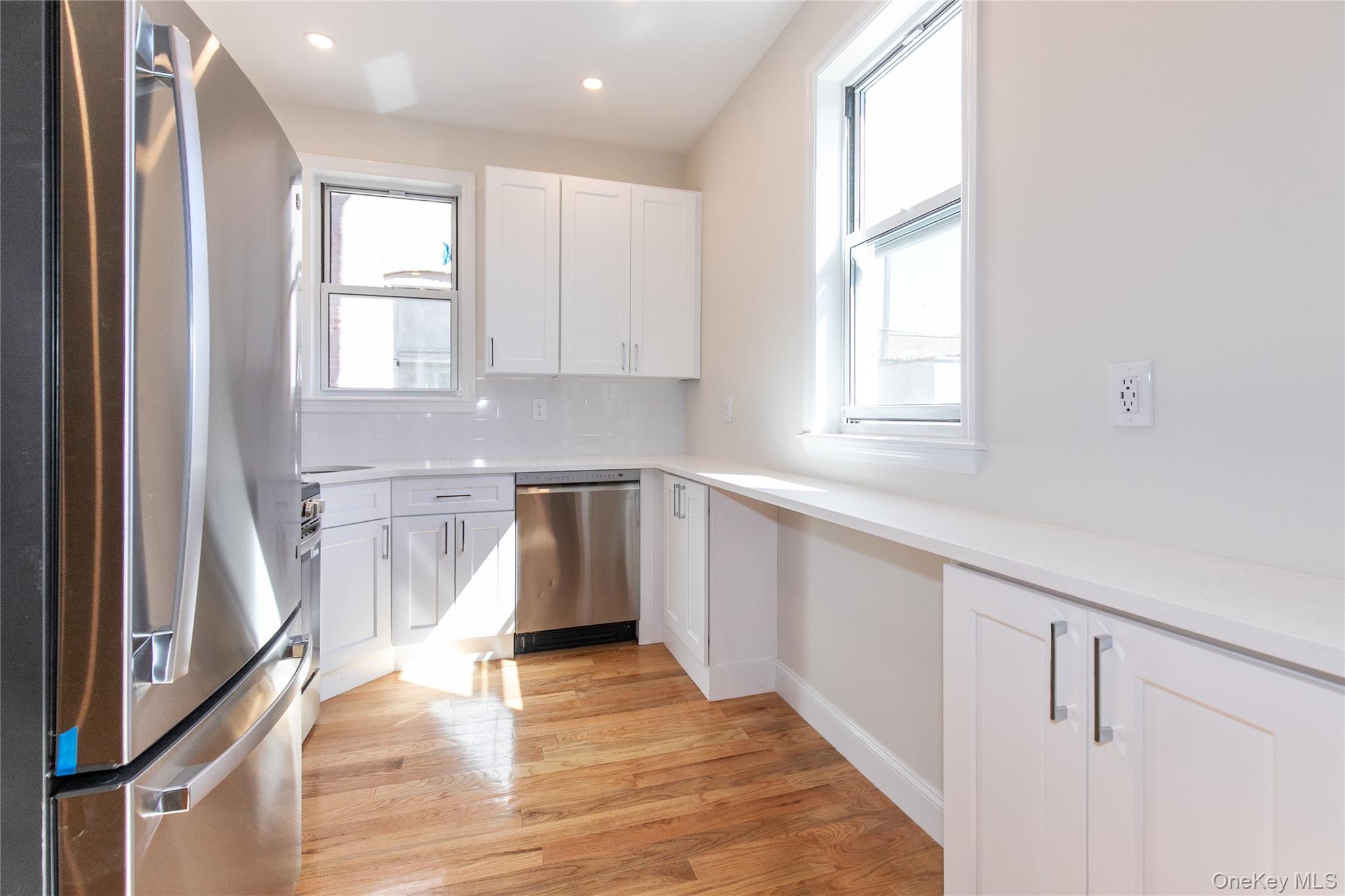 104-44 42nd Avenue Queens, NY 11368 - Photo 6 of 16 a kitchen with white cabinets and wooden floor