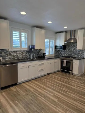 a kitchen with stainless steel appliances granite countertop a sink cabinets and wooden floor