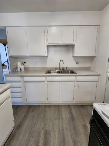 a kitchen with cabinets stainless steel appliances a sink and wooden floor