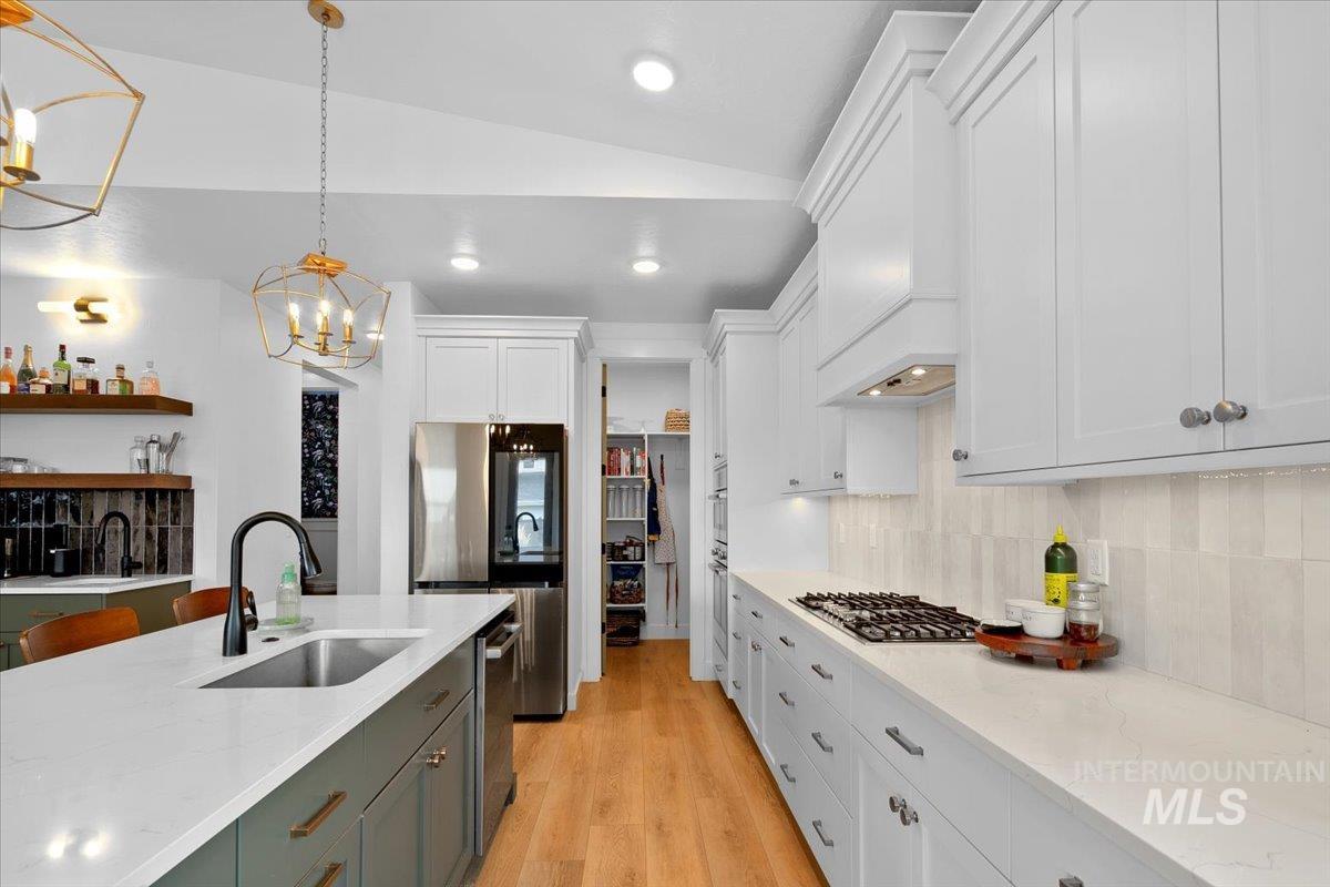 1911 East Mainacht Street Meridian, ID 83642 - Photo 13 of 49 Kitchen featuring decorative light fixtures, white cabinetry, light stone counters, appliances with stainless steel finishes, and light wood-style floors
