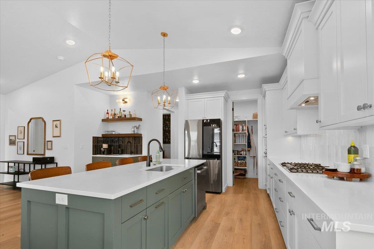 1911 East Mainacht Street Meridian, ID 83642 - Photo 14 of 49 Kitchen with lofted ceiling, white cabinetry, light wood-type flooring, hanging light fixtures, and appliances with stainless steel finishes