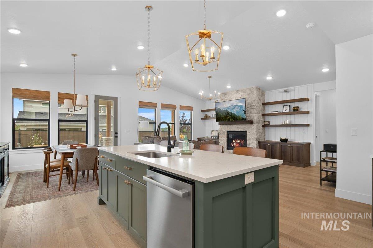 1911 East Mainacht Street Meridian, ID 83642 - Photo 17 of 49 Kitchen with a fireplace, green cabinets, a center island with sink, dishwasher, and vaulted ceiling