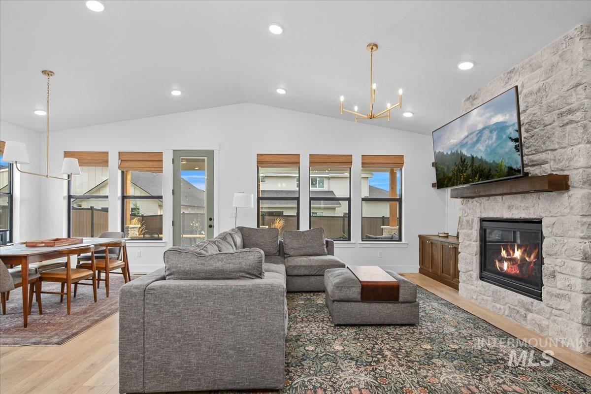 1911 East Mainacht Street Meridian, ID 83642 - Photo 21 of 49 Living room featuring a chandelier, light wood finished floors, lofted ceiling, a stone fireplace, and recessed lighting
