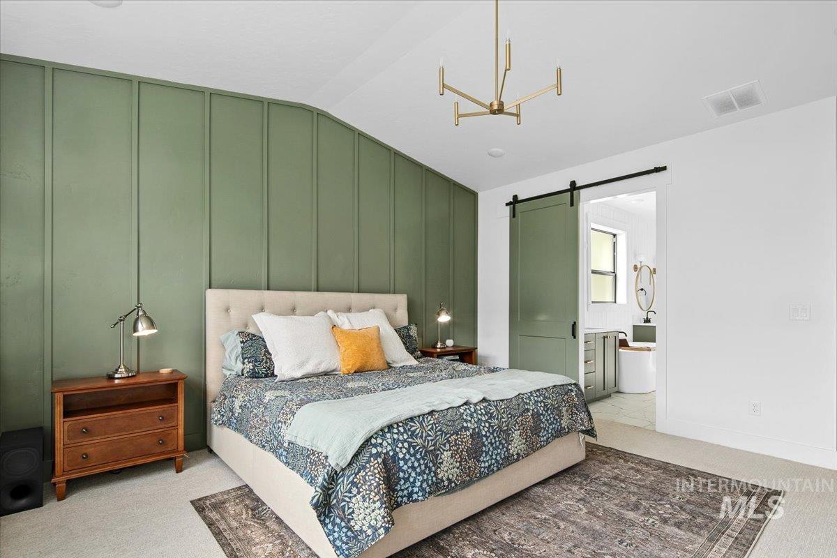 1911 East Mainacht Street Meridian, ID 83642 - Photo 25 of 49 Carpeted bedroom with a barn door, lofted ceiling, connected bathroom, and a decorative wall