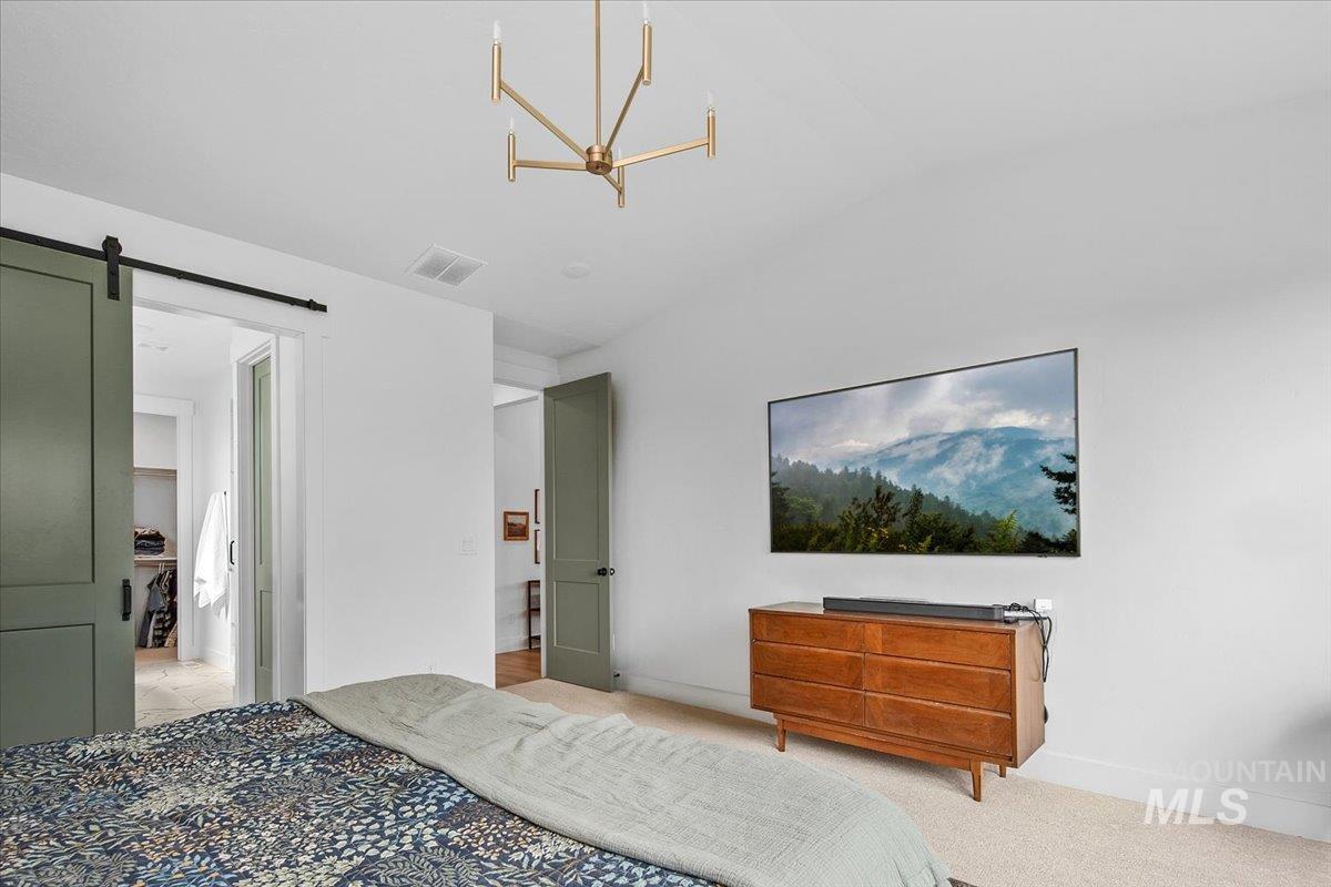 1911 East Mainacht Street Meridian, ID 83642 - Photo 26 of 49 Bedroom with a barn door, light carpet, and a chandelier