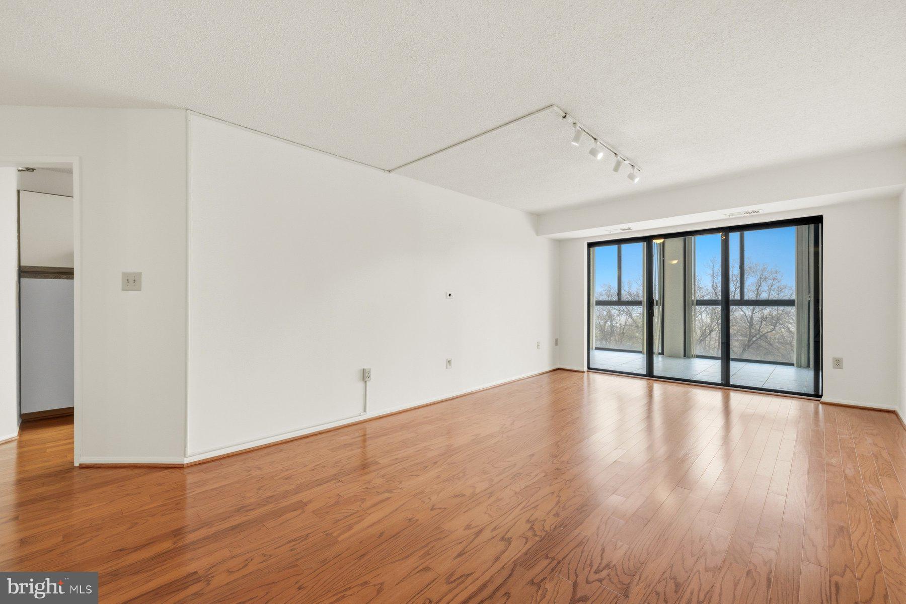 15107 Interlachen Drive, Unit 2801 Silver Spring, MD 20906 - Photo 6 of 50 a view of an empty room with wooden floor and a window