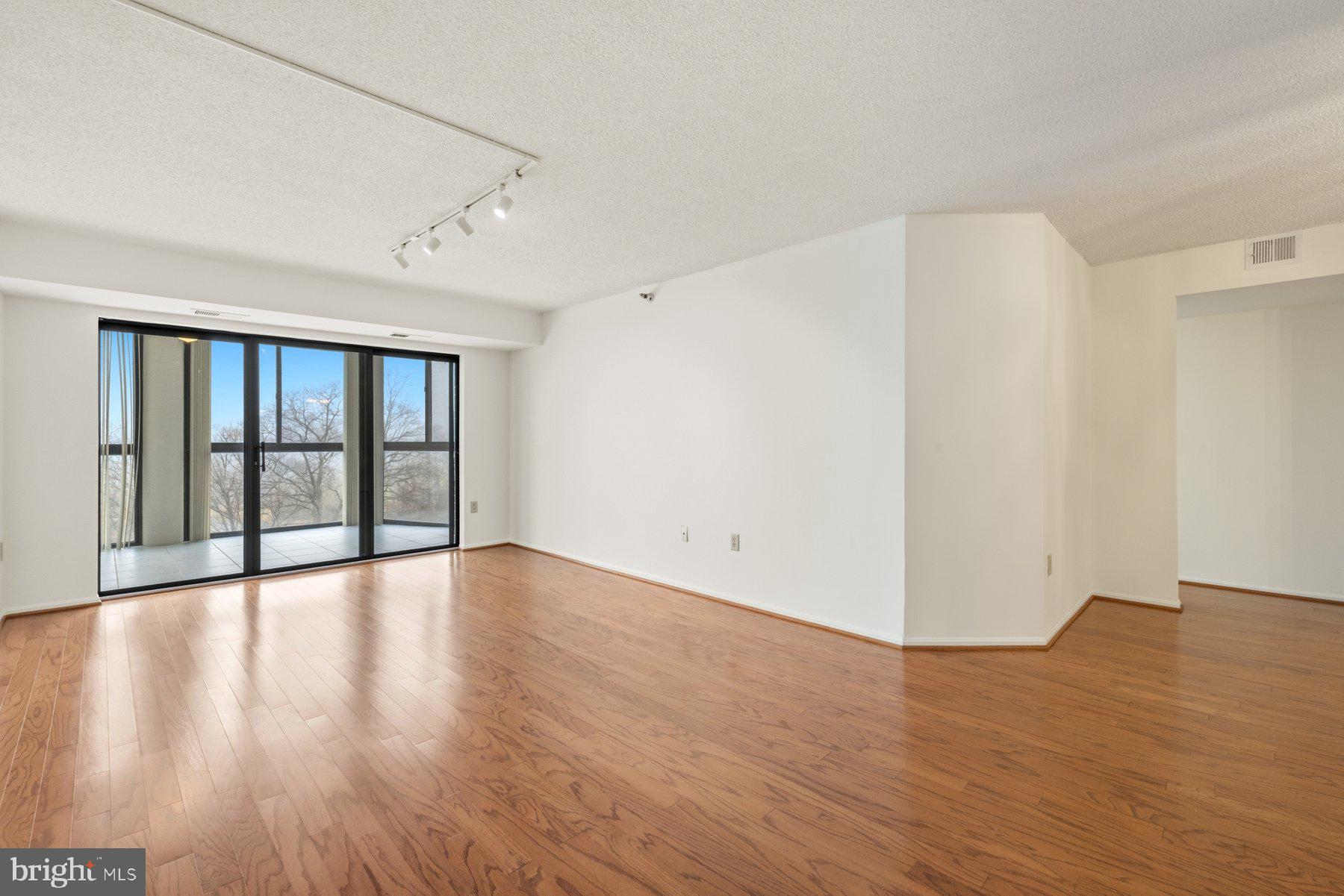 15107 Interlachen Drive, Unit 2801 Silver Spring, MD 20906 - Photo 8 of 50 a view of an empty room with wooden floor and a window