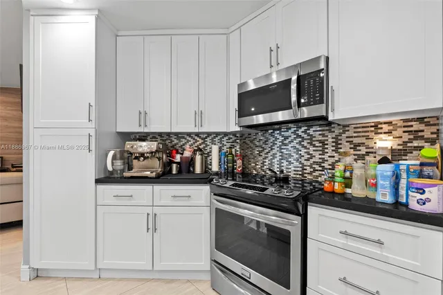 a kitchen with stainless steel appliances granite countertop white cabinets and black appliances