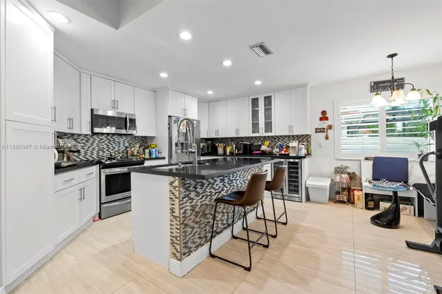 a kitchen with stainless steel appliances kitchen island granite countertop a stove top oven a sink a dining table and chairs