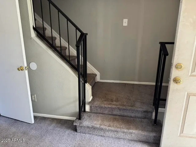 a view of staircase with railing and white walls