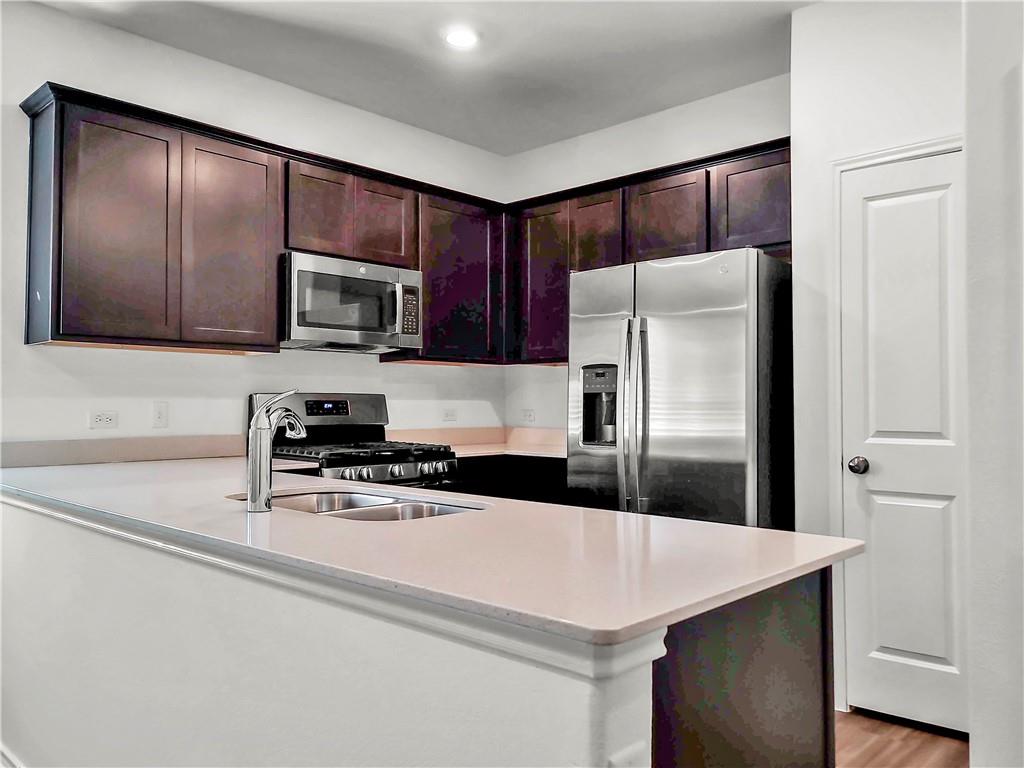251 Geode Glen Maxwell, TX 78656 - Photo 4 of 16 a kitchen with kitchen island a counter top space cabinets and stainless steel appliances
