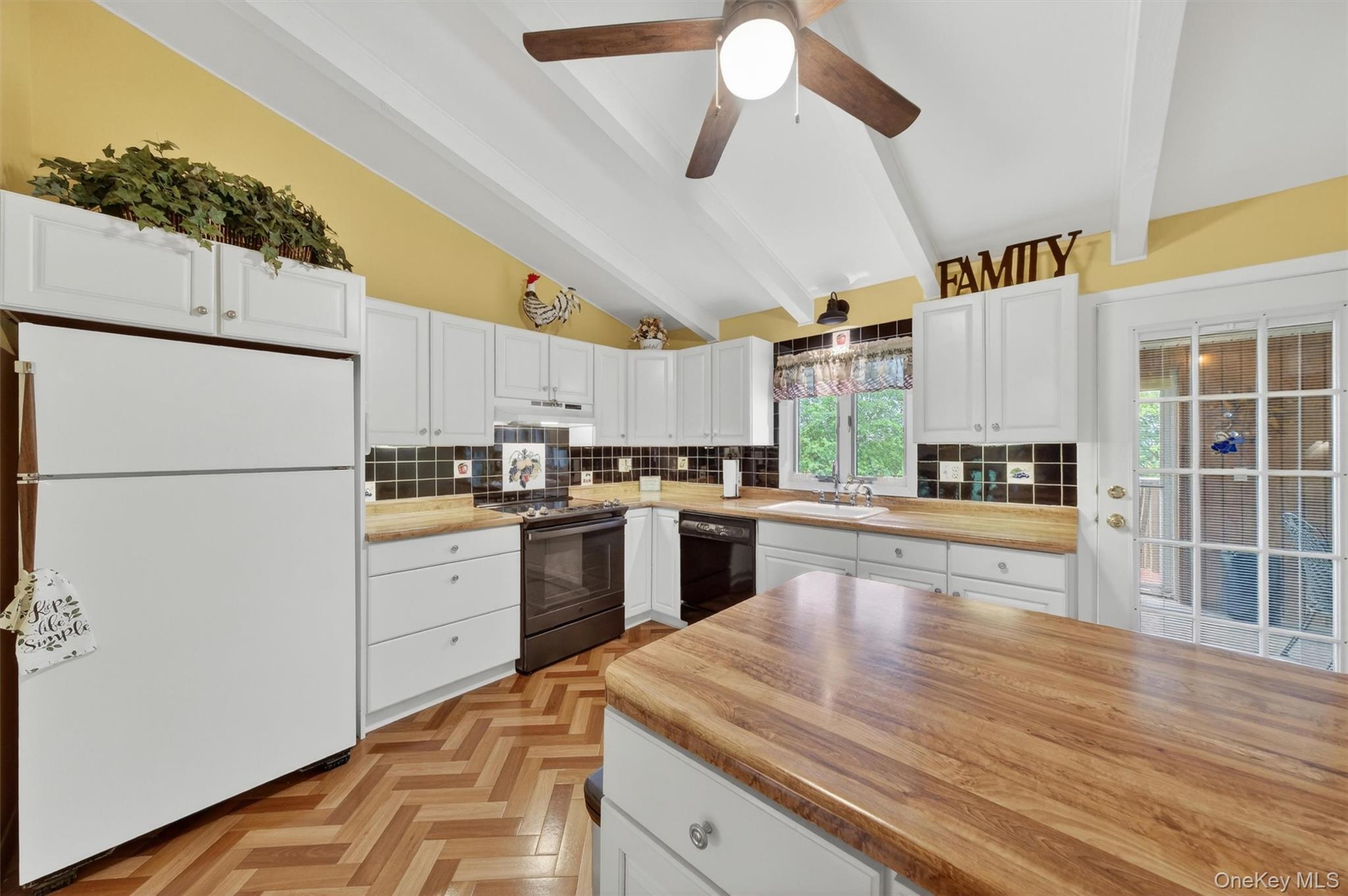1 Rockledge Road Poughkeepsie, NY 12601 - Photo 13 of 36 Kitchen featuring vaulted ceilings with exposed beams, wood-finish flooring in a herringbone pattern, white cabinetry, breakfast bar, tile backsplash, cabinet lighting and light wood-finish countertops